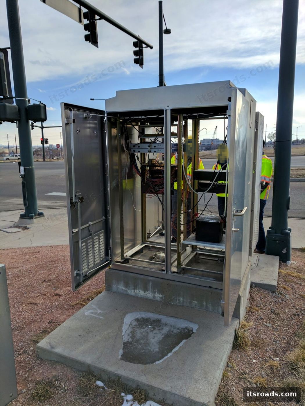 Open pole-mounted roadside electronics cabinet during integration