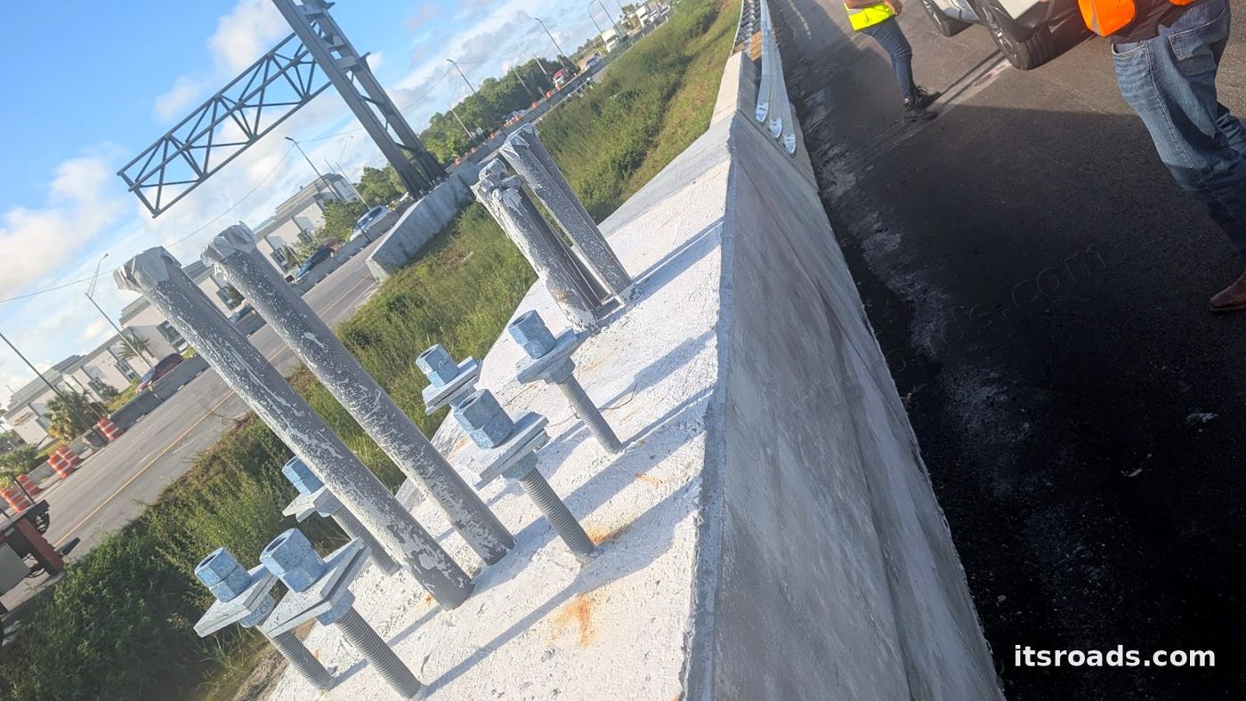 Conduit stubs and anchor bolts on a concrete median barrier awaiting a camera pole on I-4
